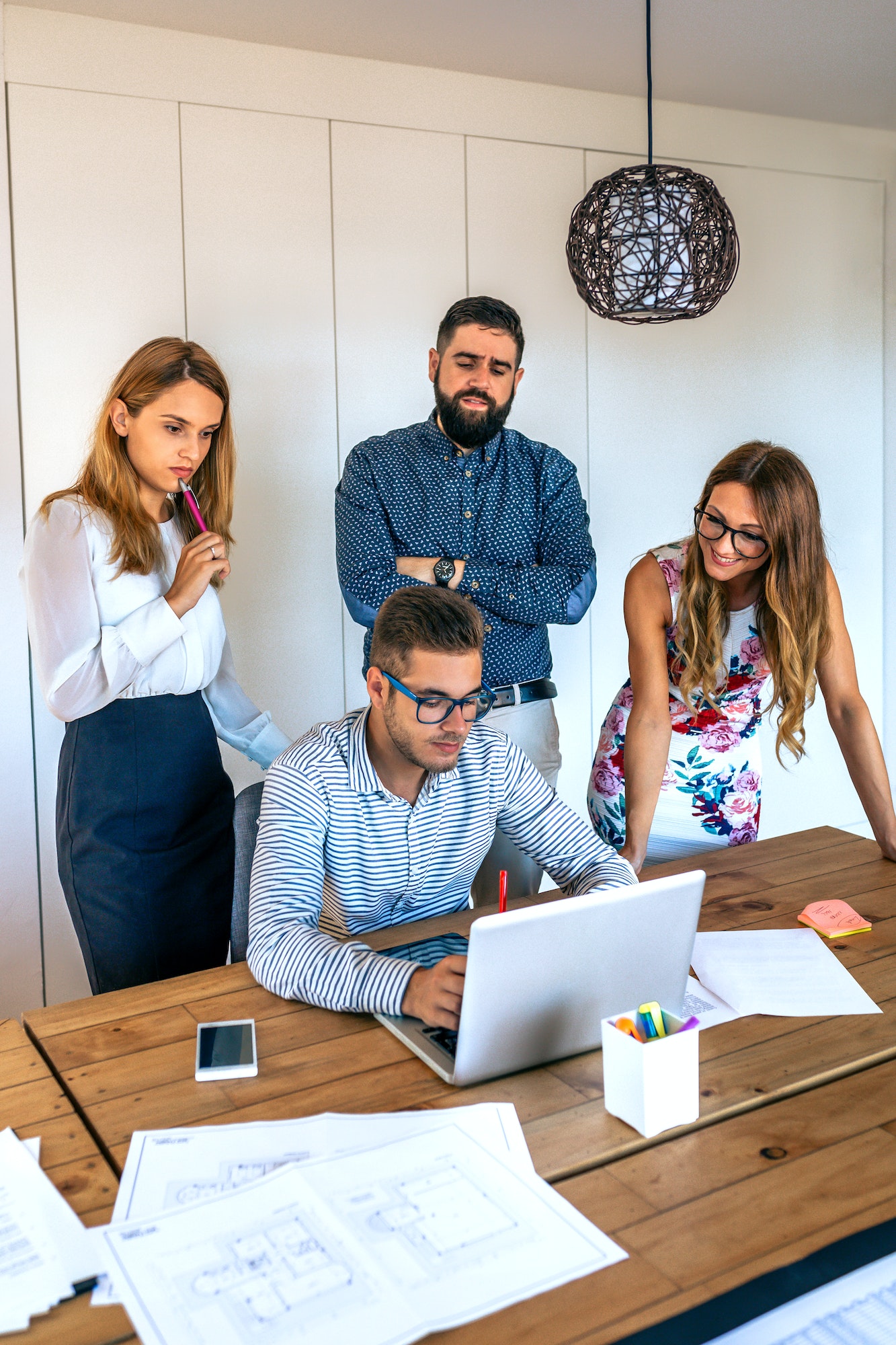 Businesspeople in a meeting standing reviewing a project on the laptop