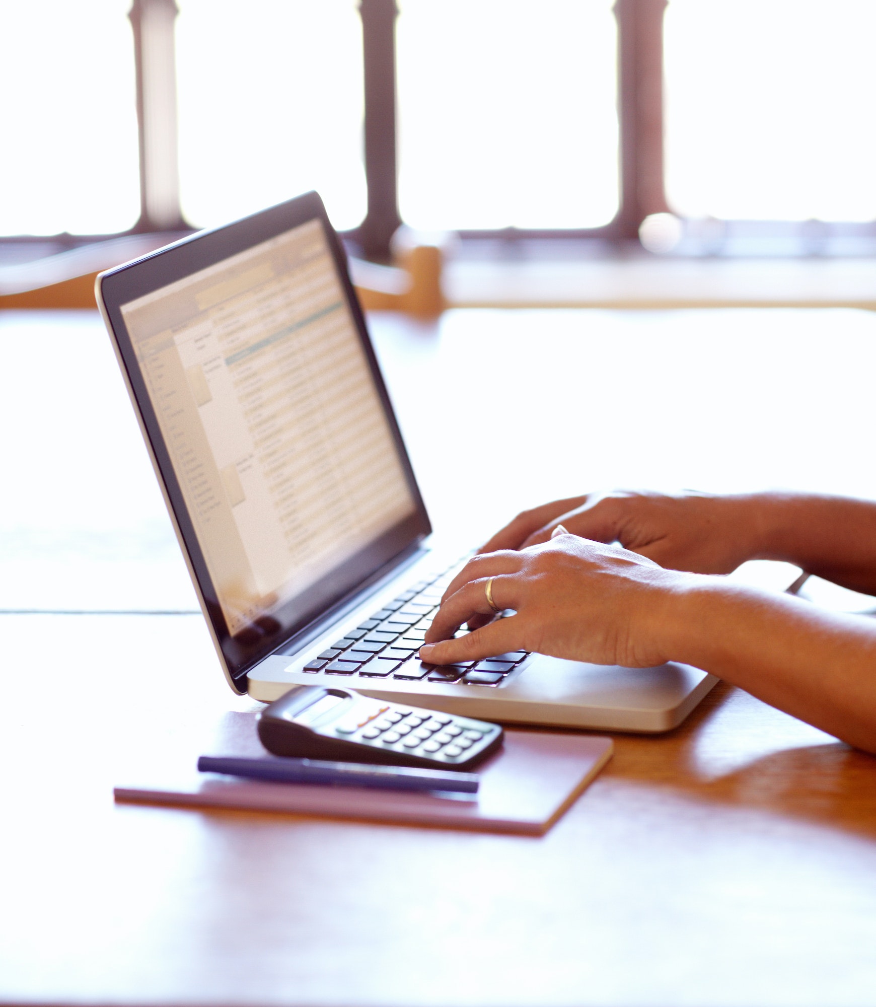 Calculating her tax for the month. Closeup detail view of female hands using a laptop.